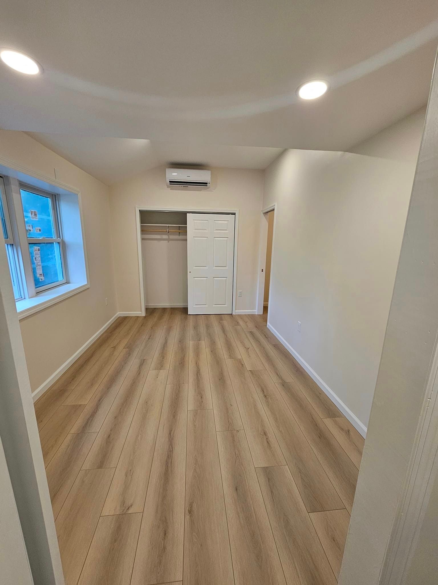 A large empty room with hardwood floors and white walls.