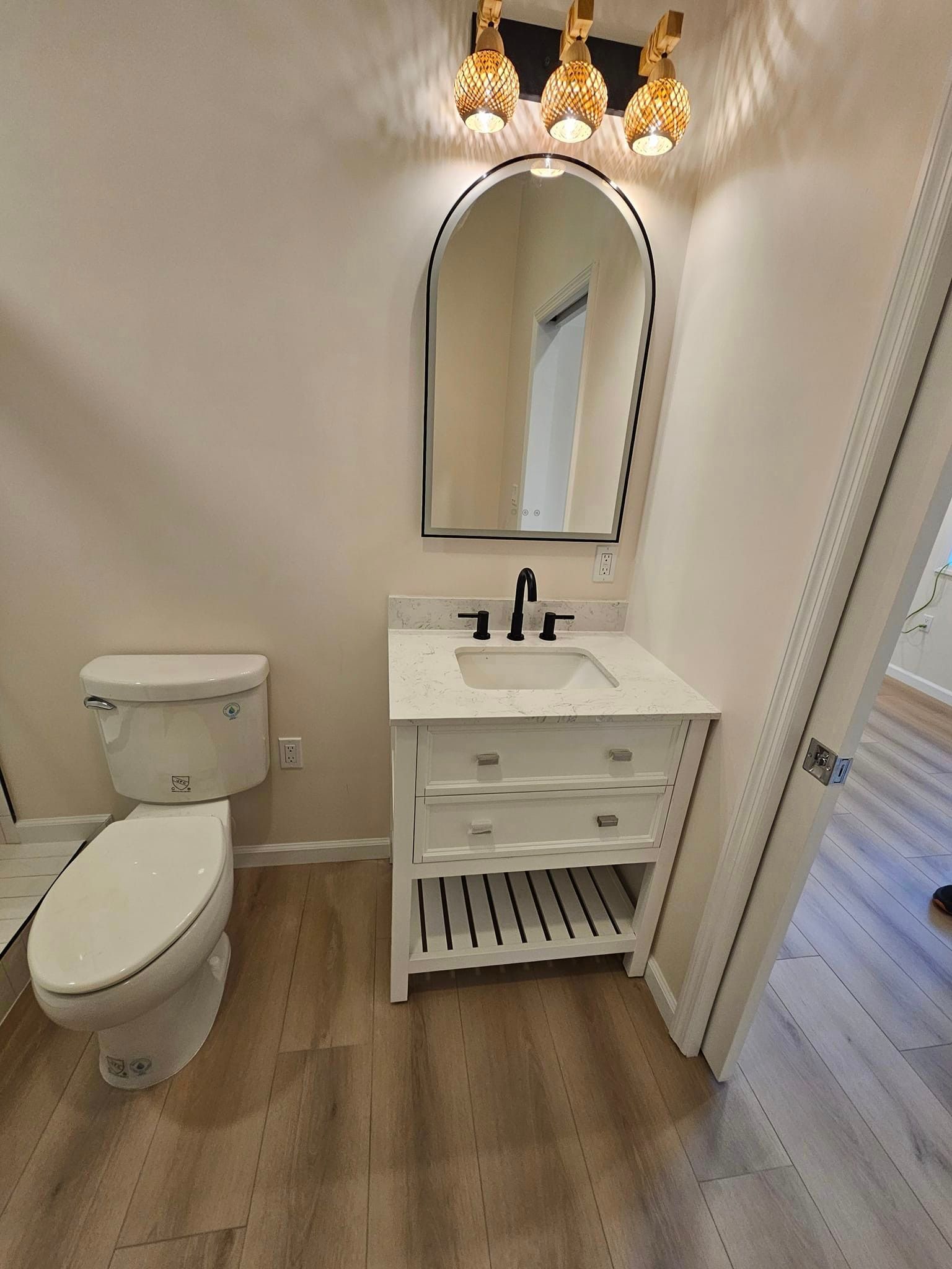 A bathroom with a toilet , sink and mirror.