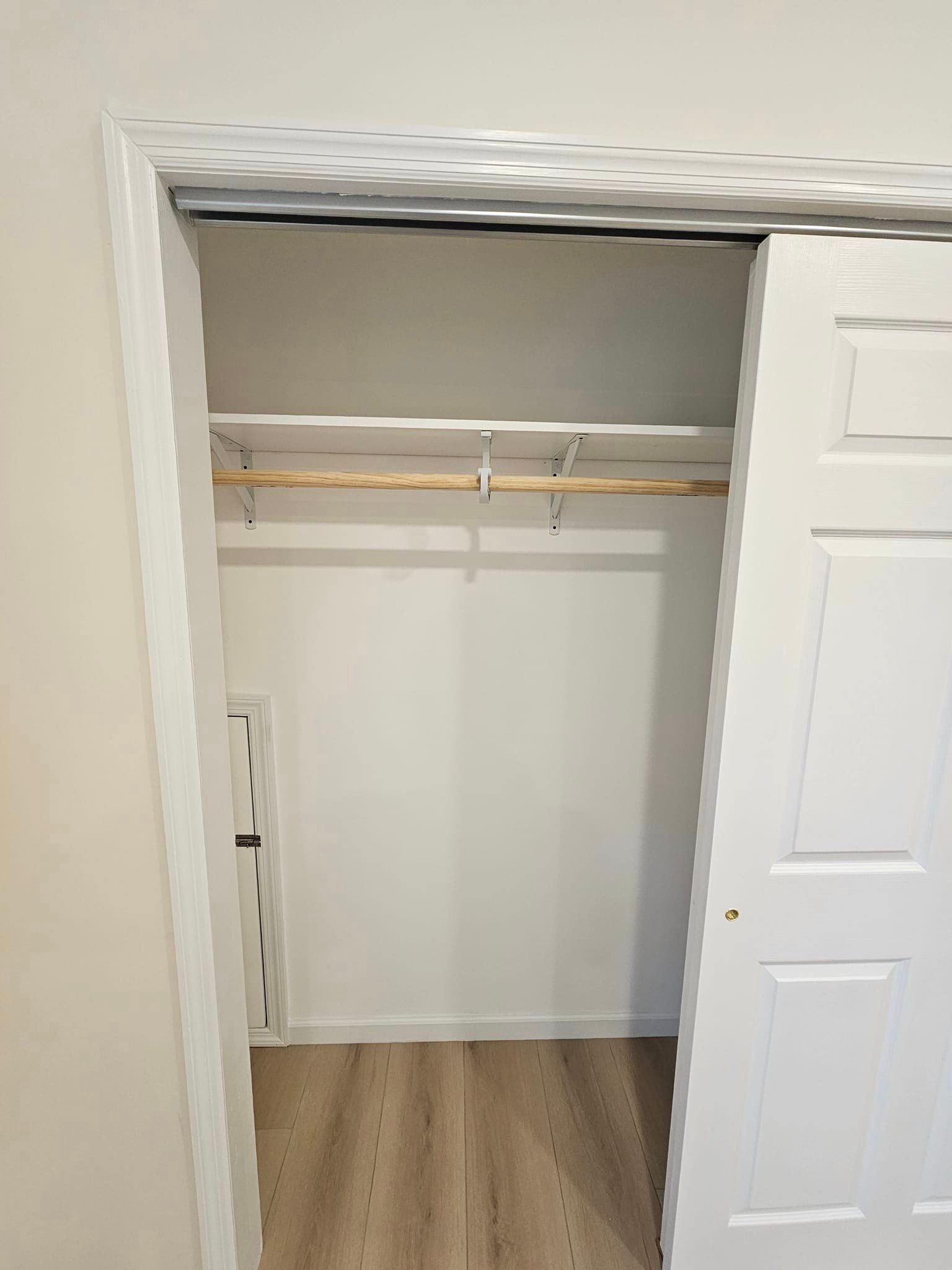 A closet with a wooden floor and a white door.