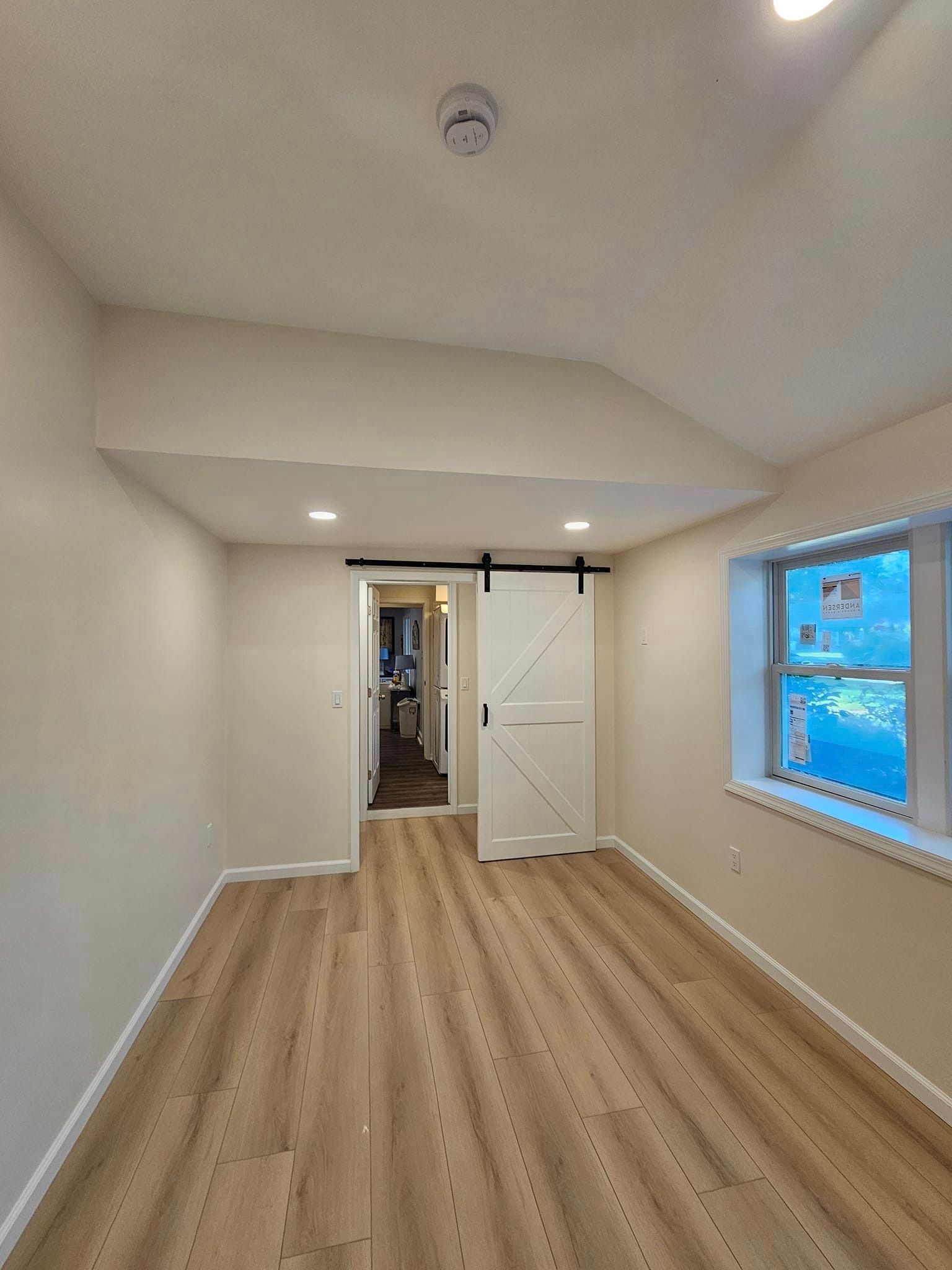An empty room with a sliding barn door and two windows.