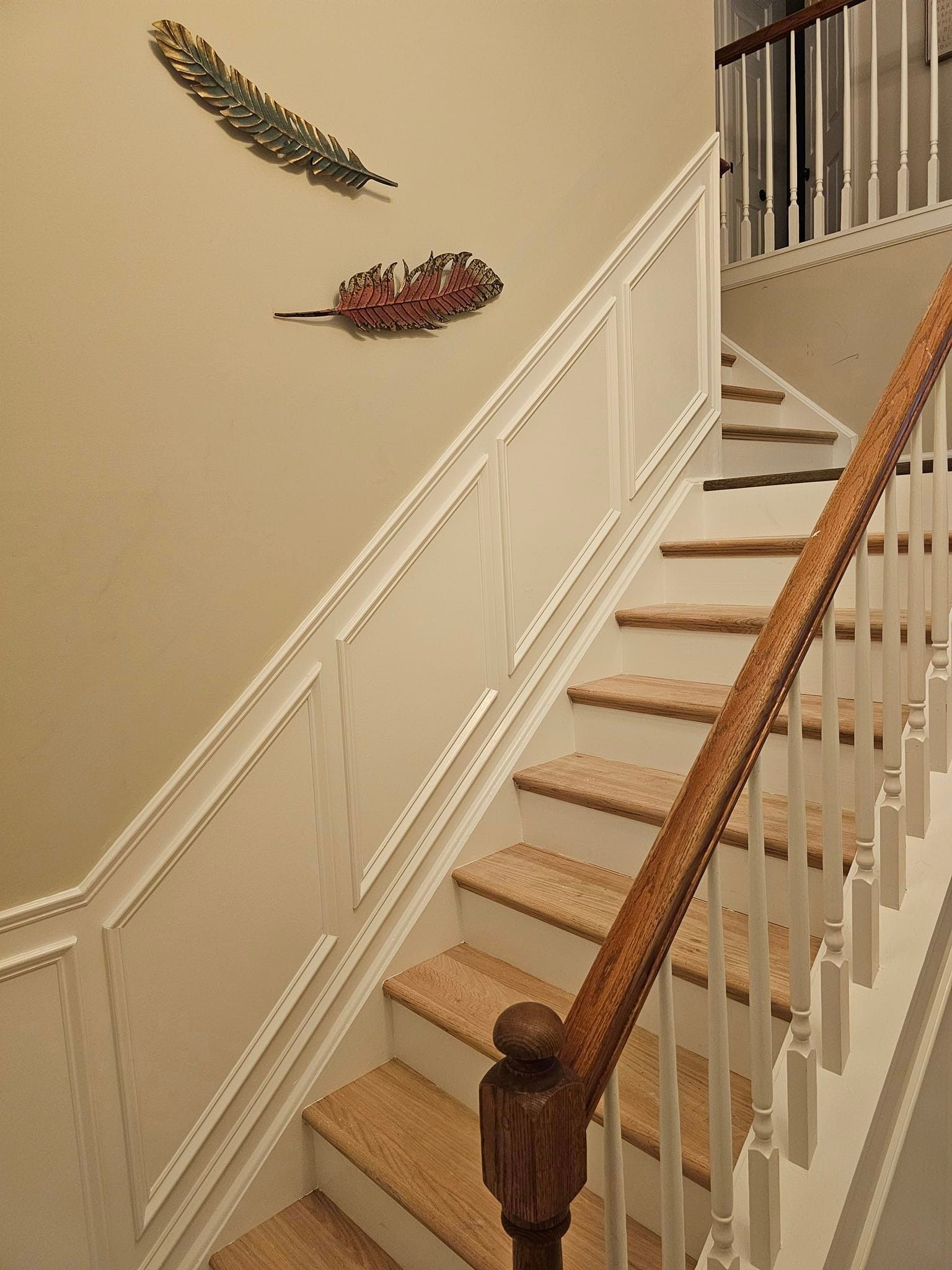A staircase with two feathers on the wall above it