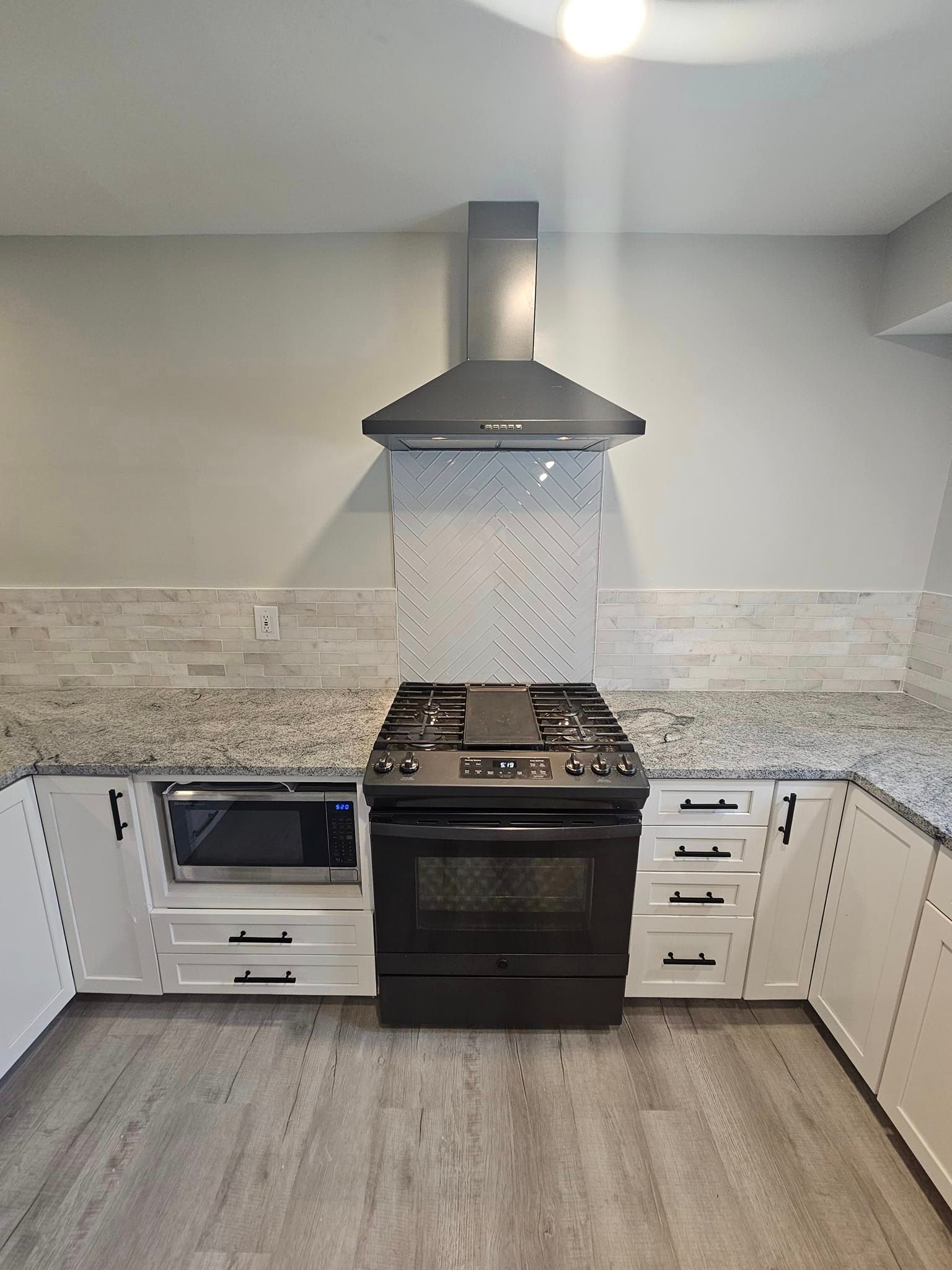 A kitchen with a black stove and a hood above it.