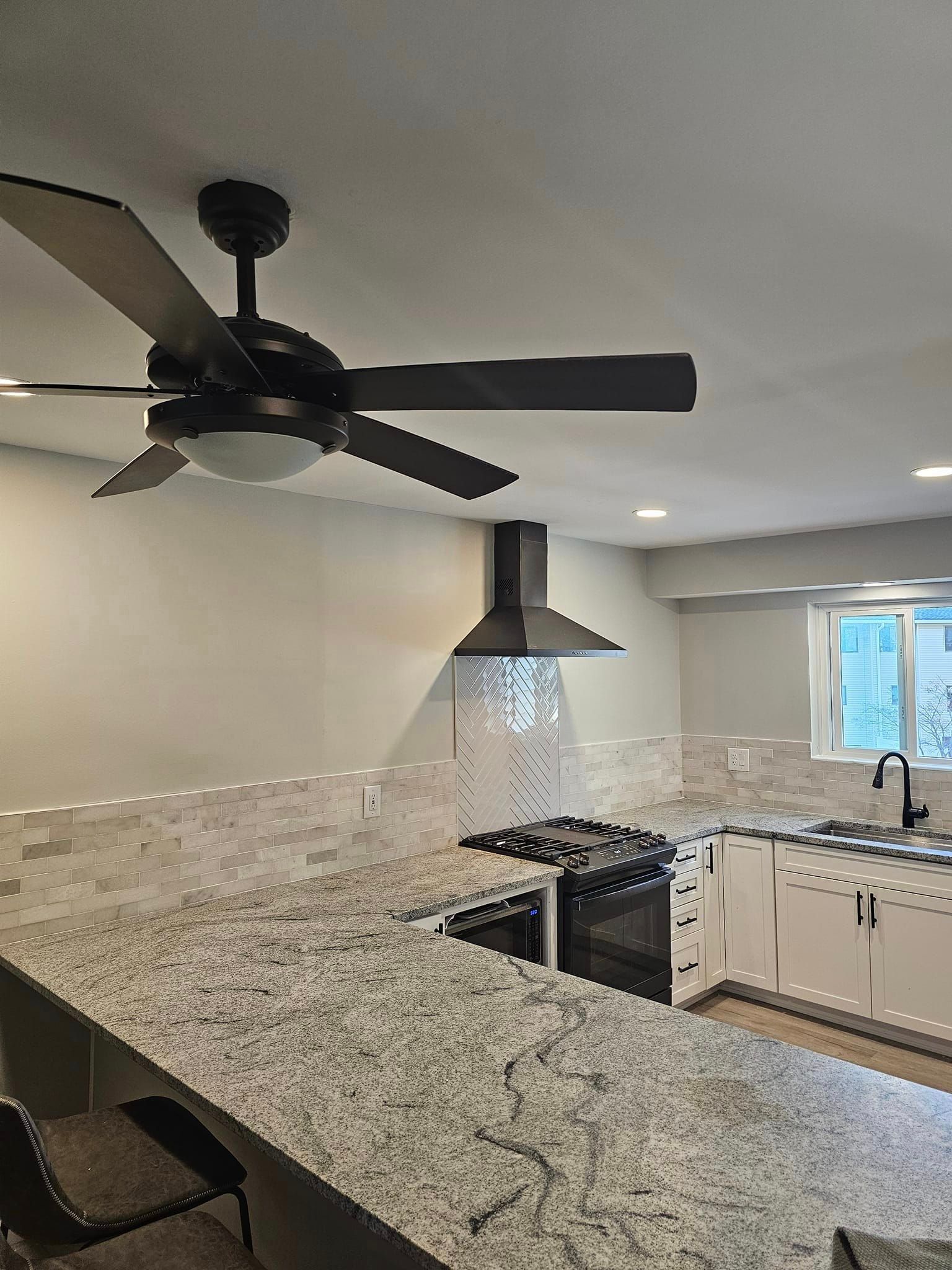 A kitchen with granite counter tops and a ceiling fan.