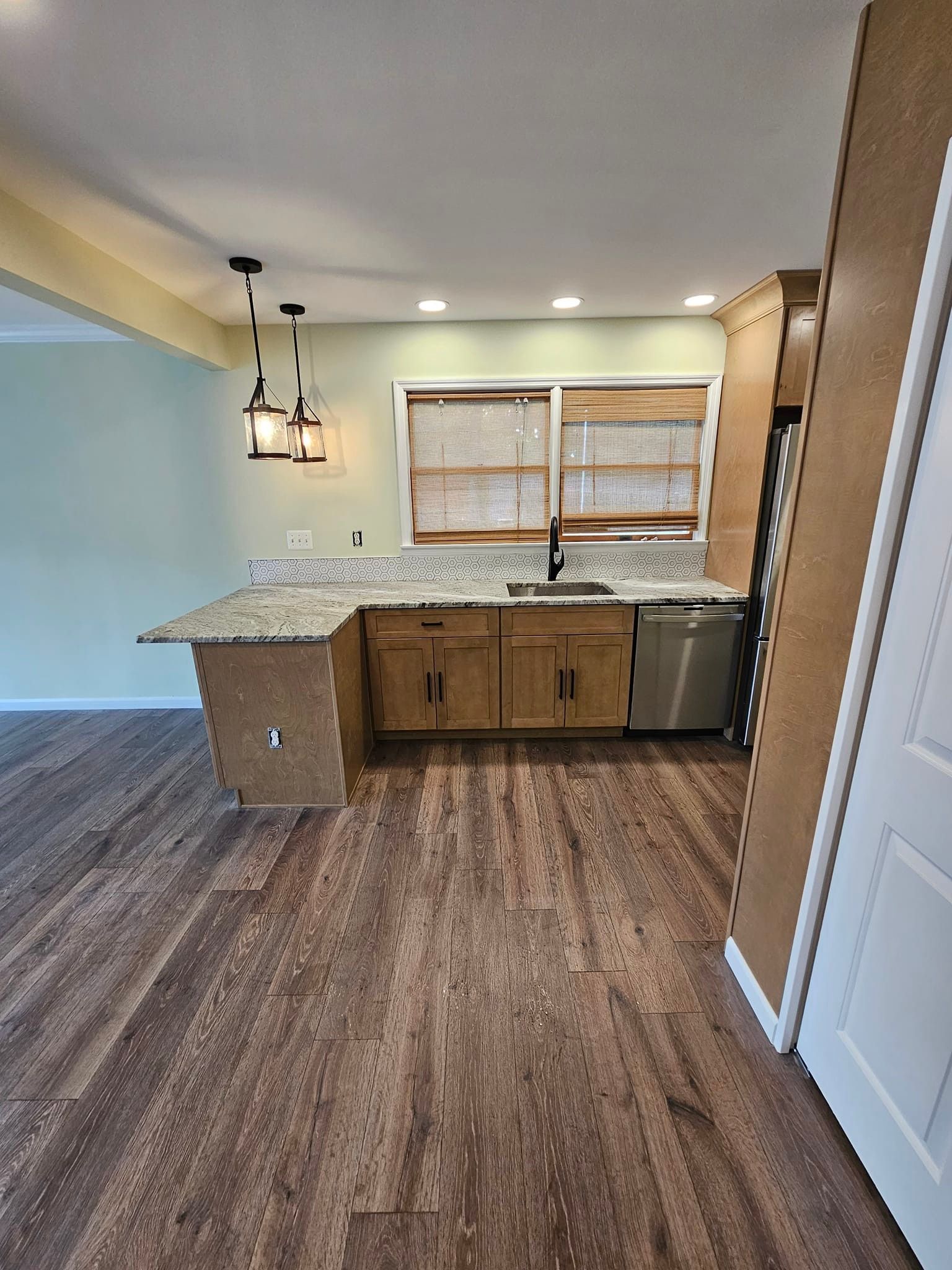A kitchen with hardwood floors, granite counter tops, and stainless steel appliances.