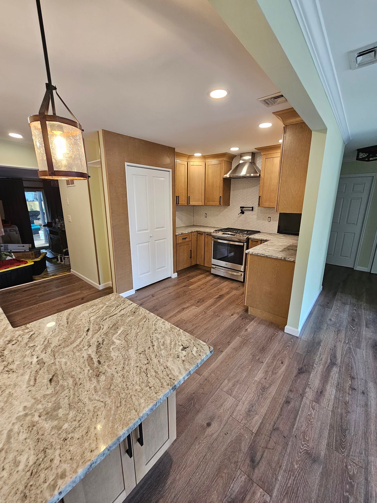 A kitchen with granite counter tops, wooden cabinets, a stove and a sink.
