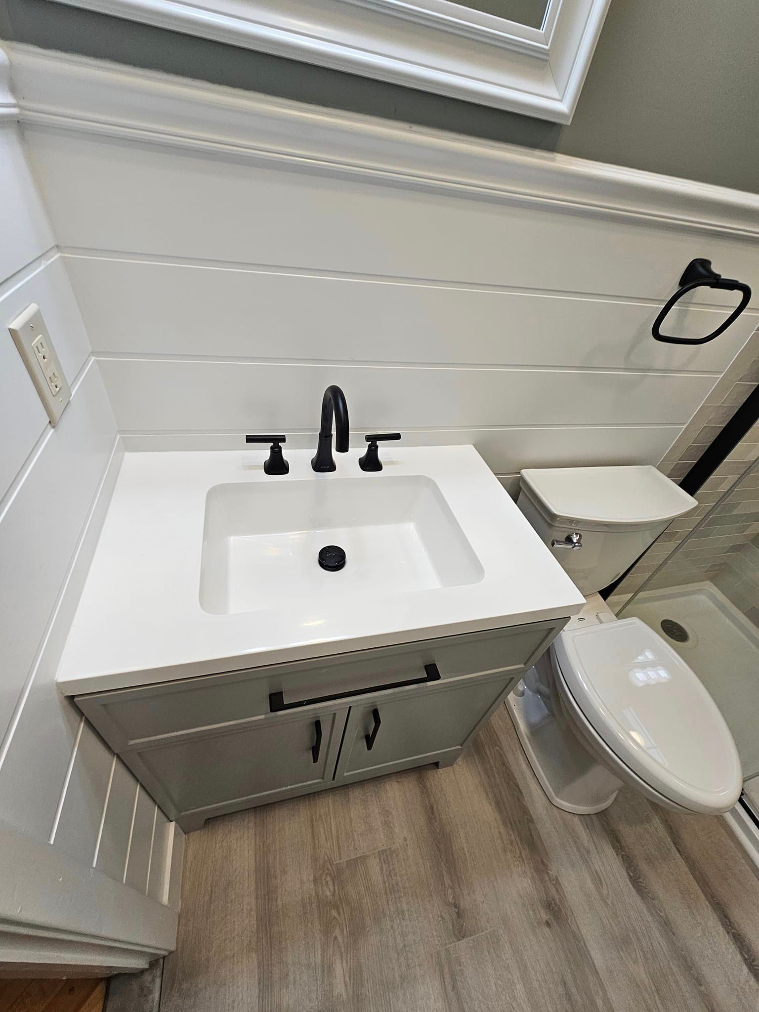 A bathroom with a sink, toilet and mirror.