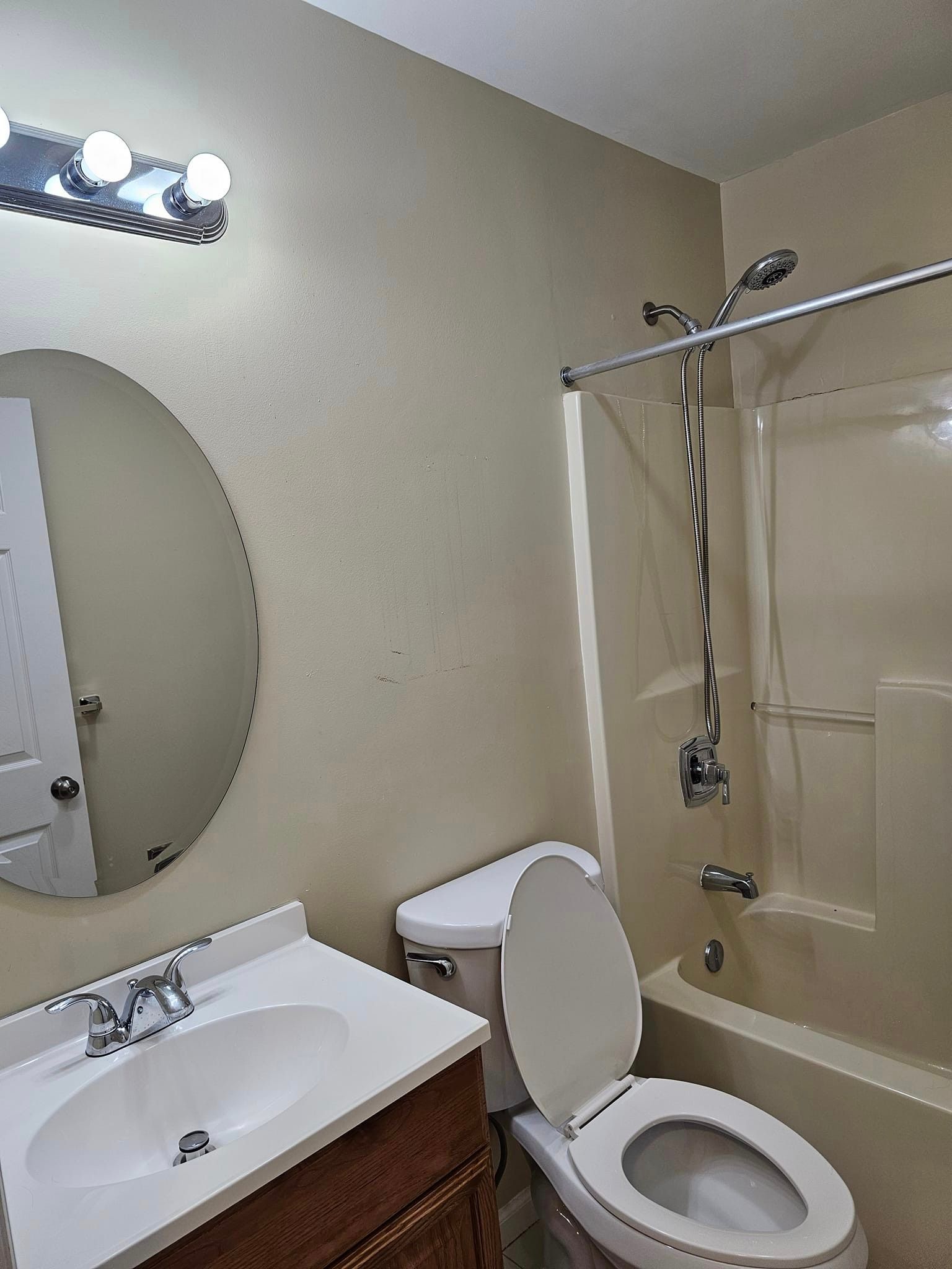 A bathroom with a toilet, sink, mirror and bathtub.