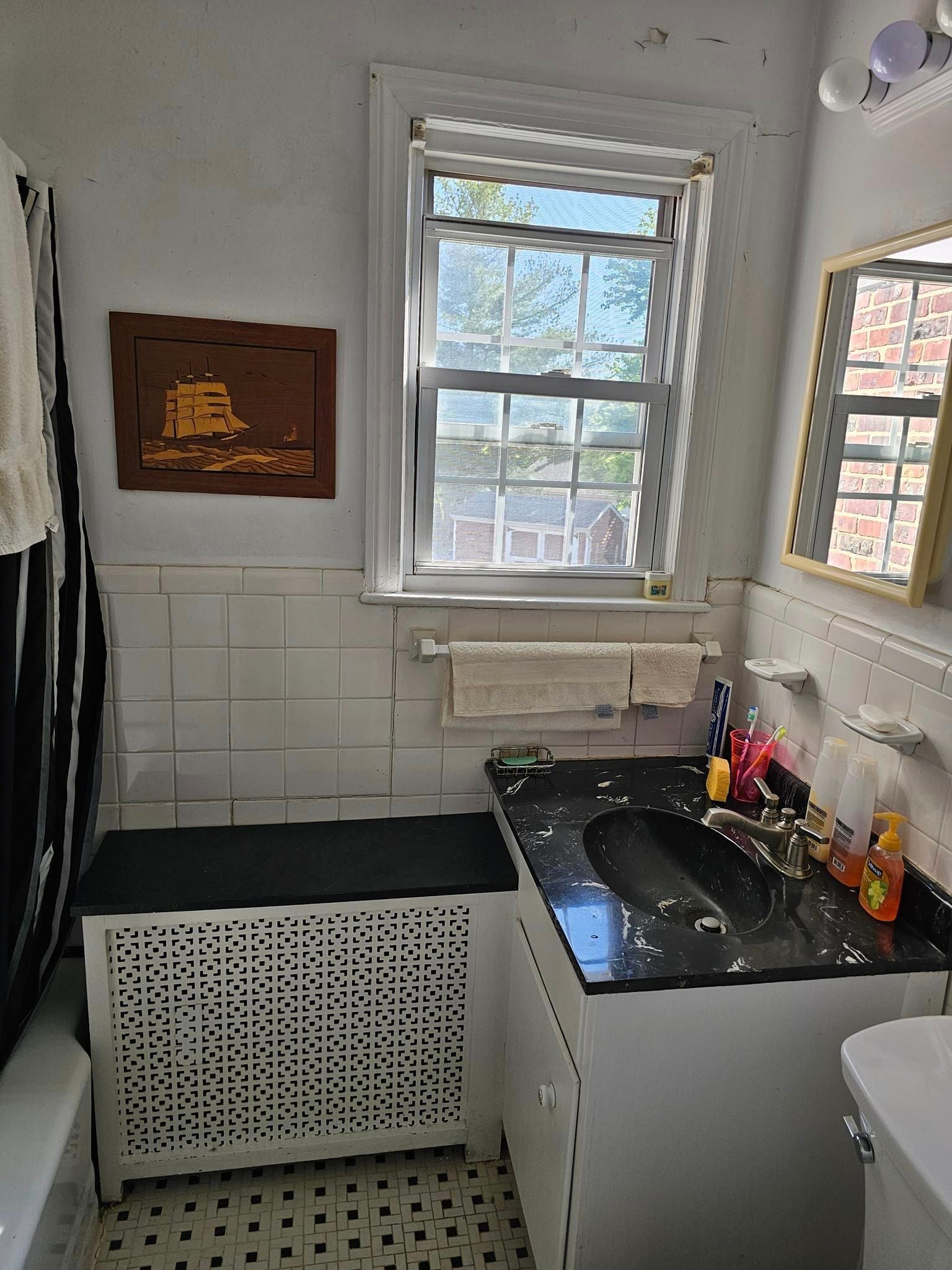 A bathroom with a sink, toilet, mirror and window.