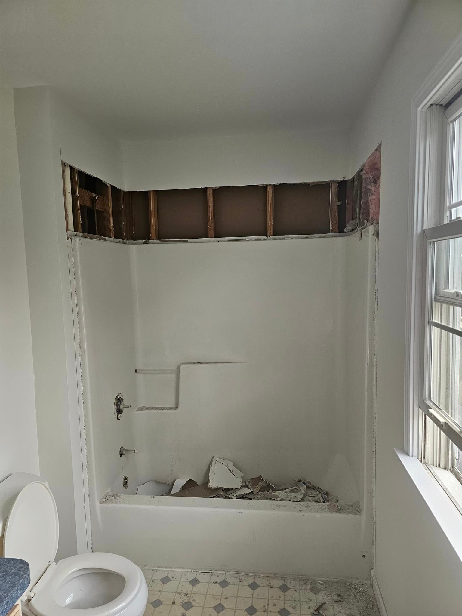 A bathroom with a toilet, bathtub and window.