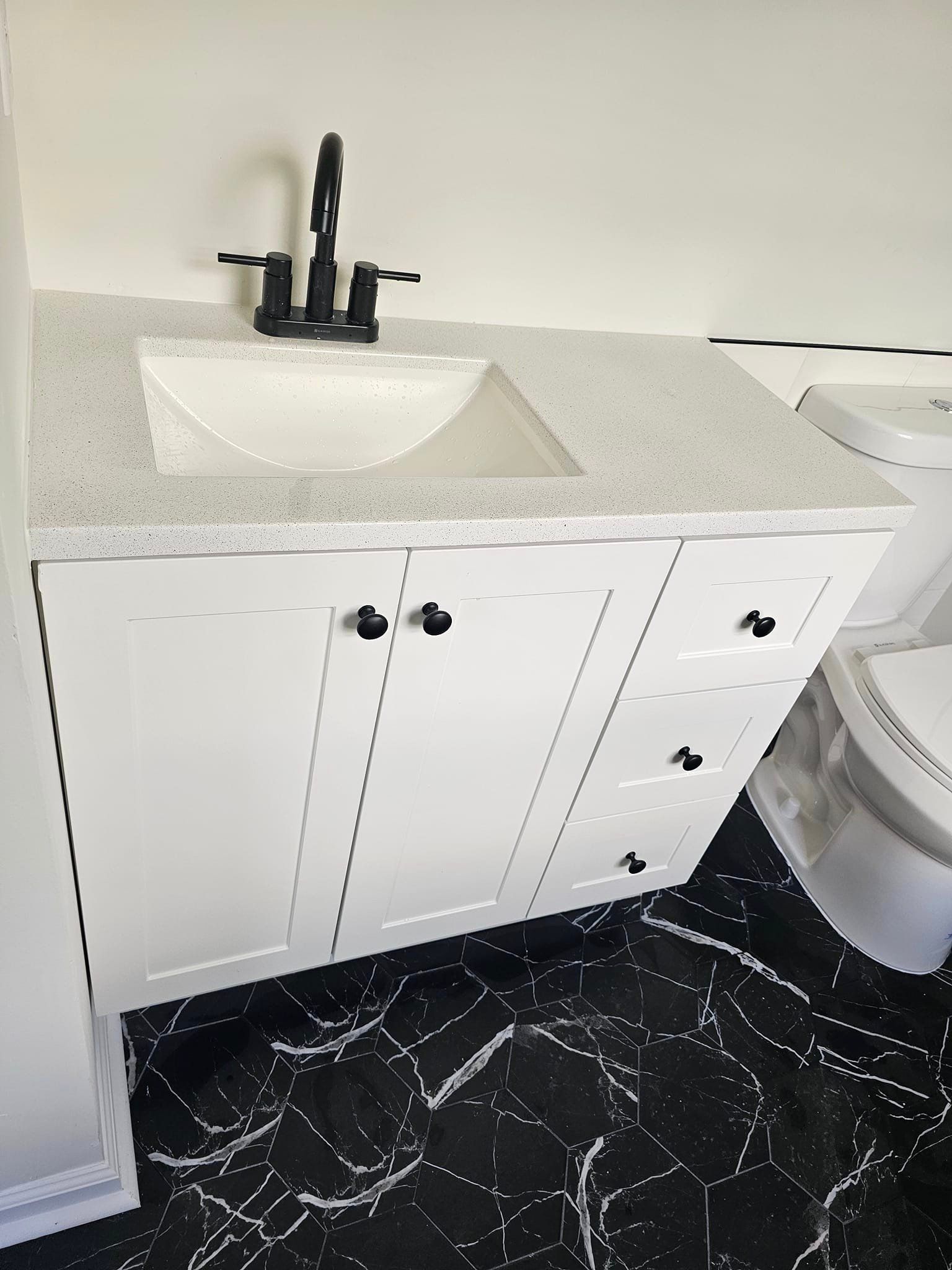 A bathroom with a sink, toilet and black and white tile floor.