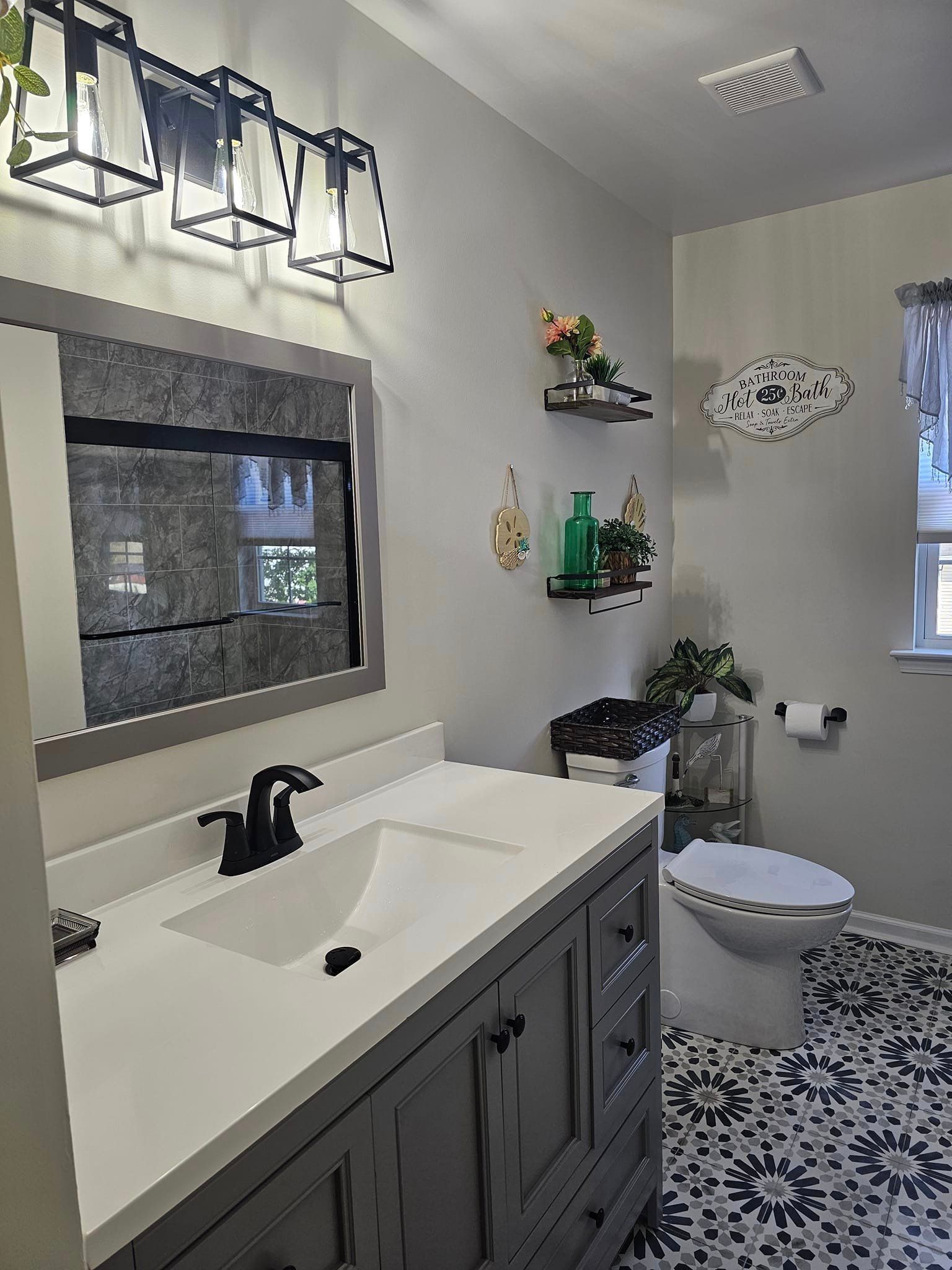A bathroom with a sink, toilet and mirror.