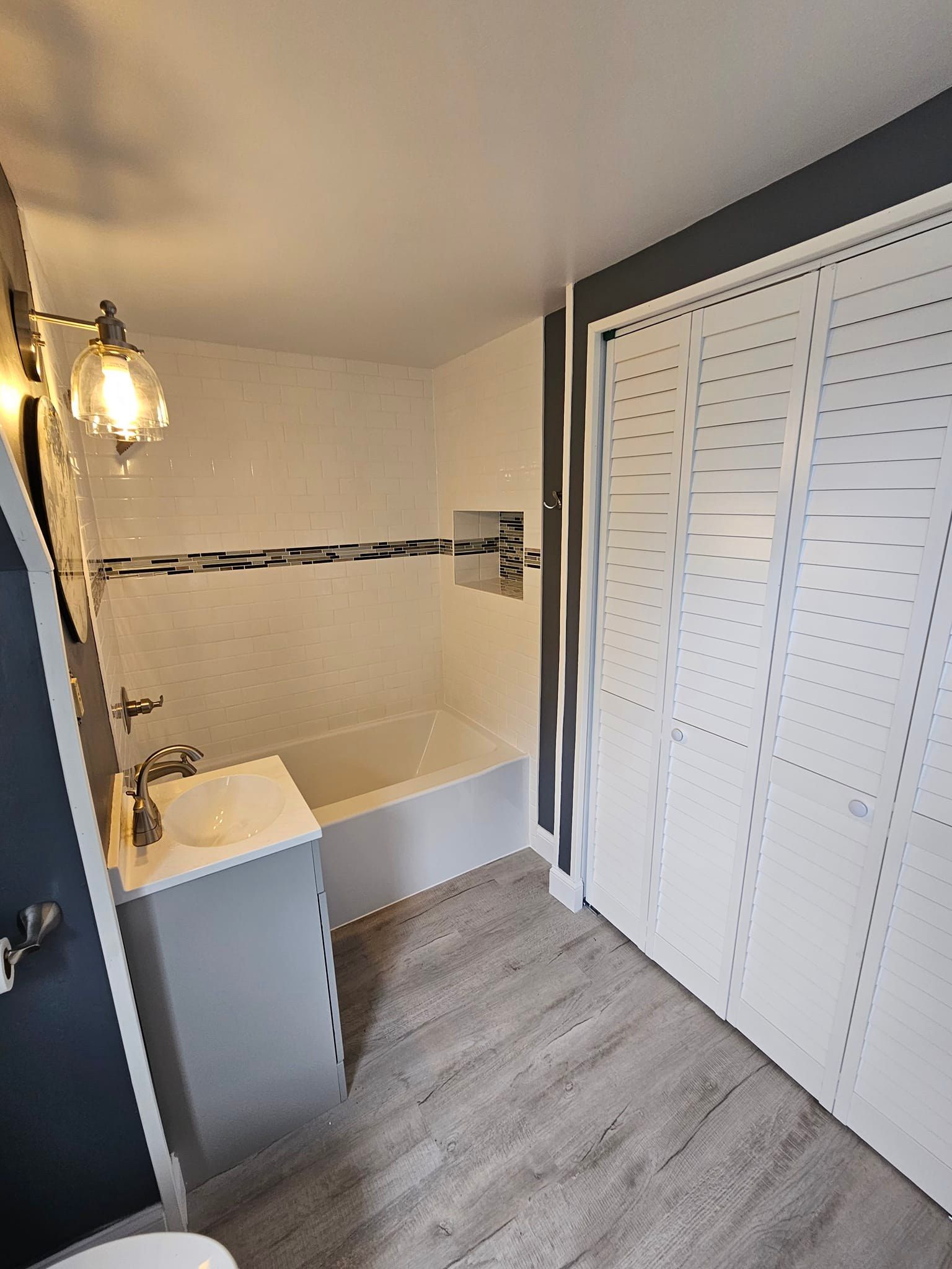 A bathroom with a tub, sink, toilet and closet.