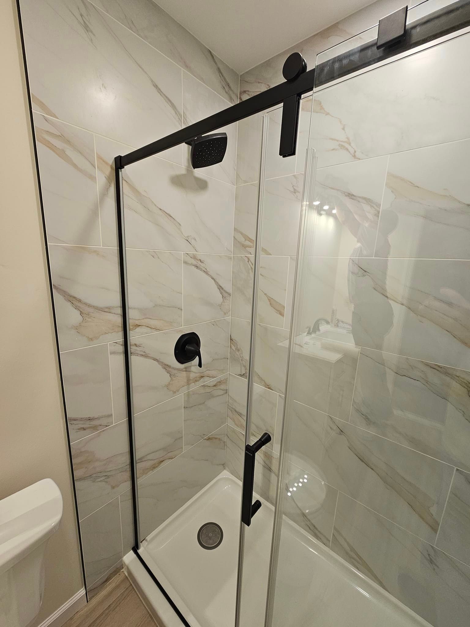 A bathroom with a sliding glass shower door and a bathtub.