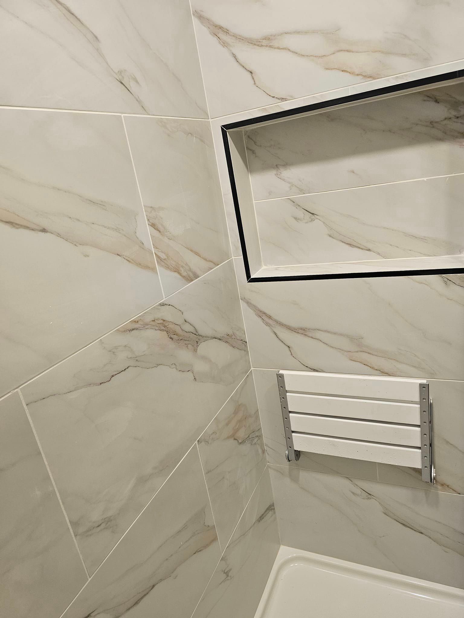 A bathroom with marble tiles and a shower stall.