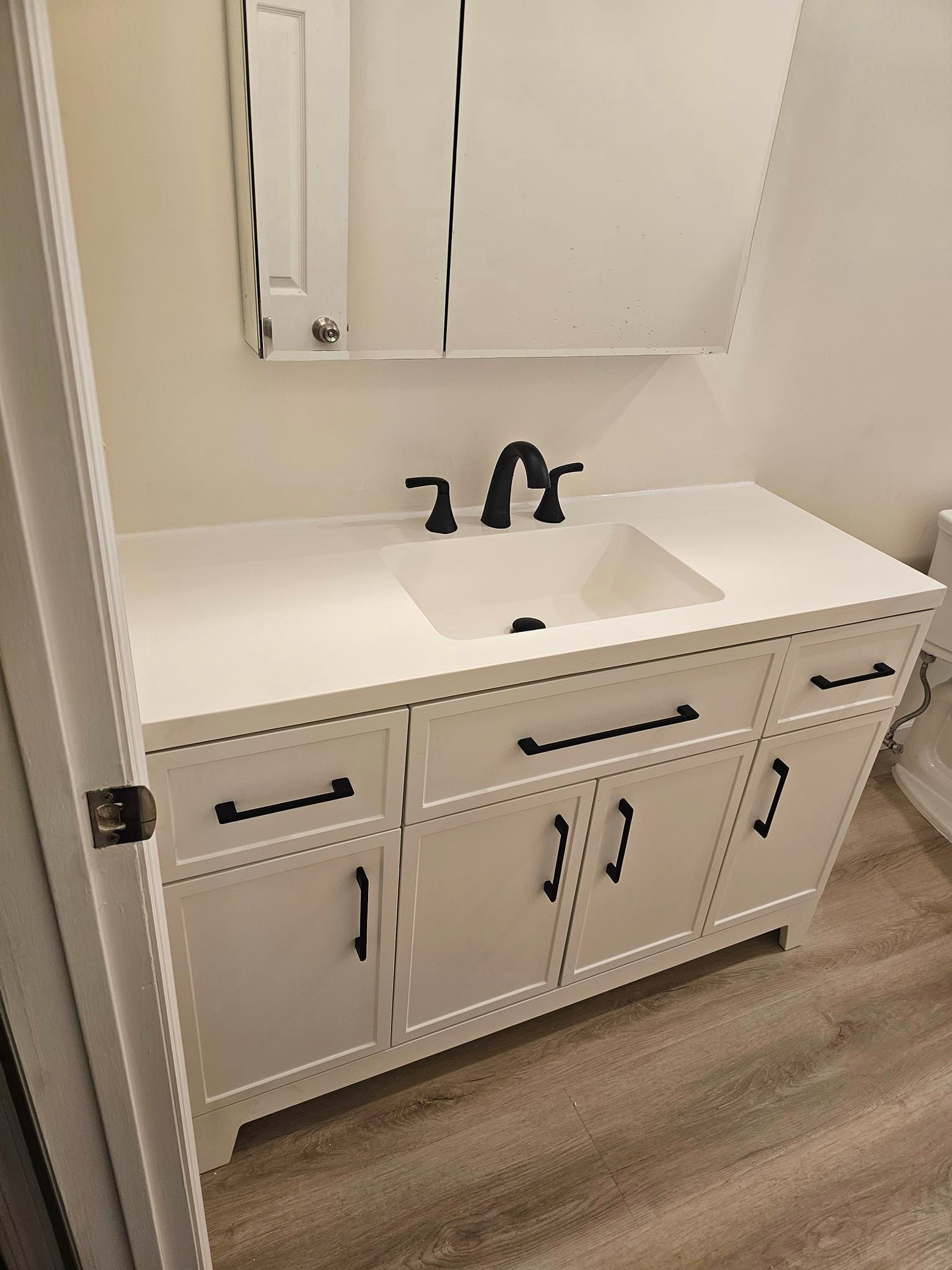 A bathroom with a sink, mirror and cabinets.