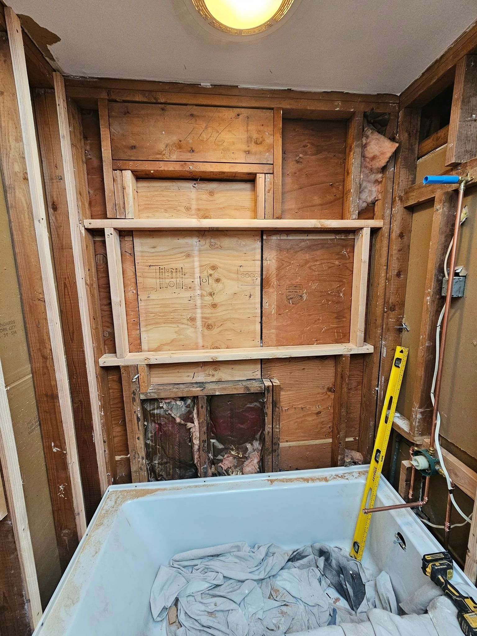 A bathroom under construction with a bathtub and a yellow level.