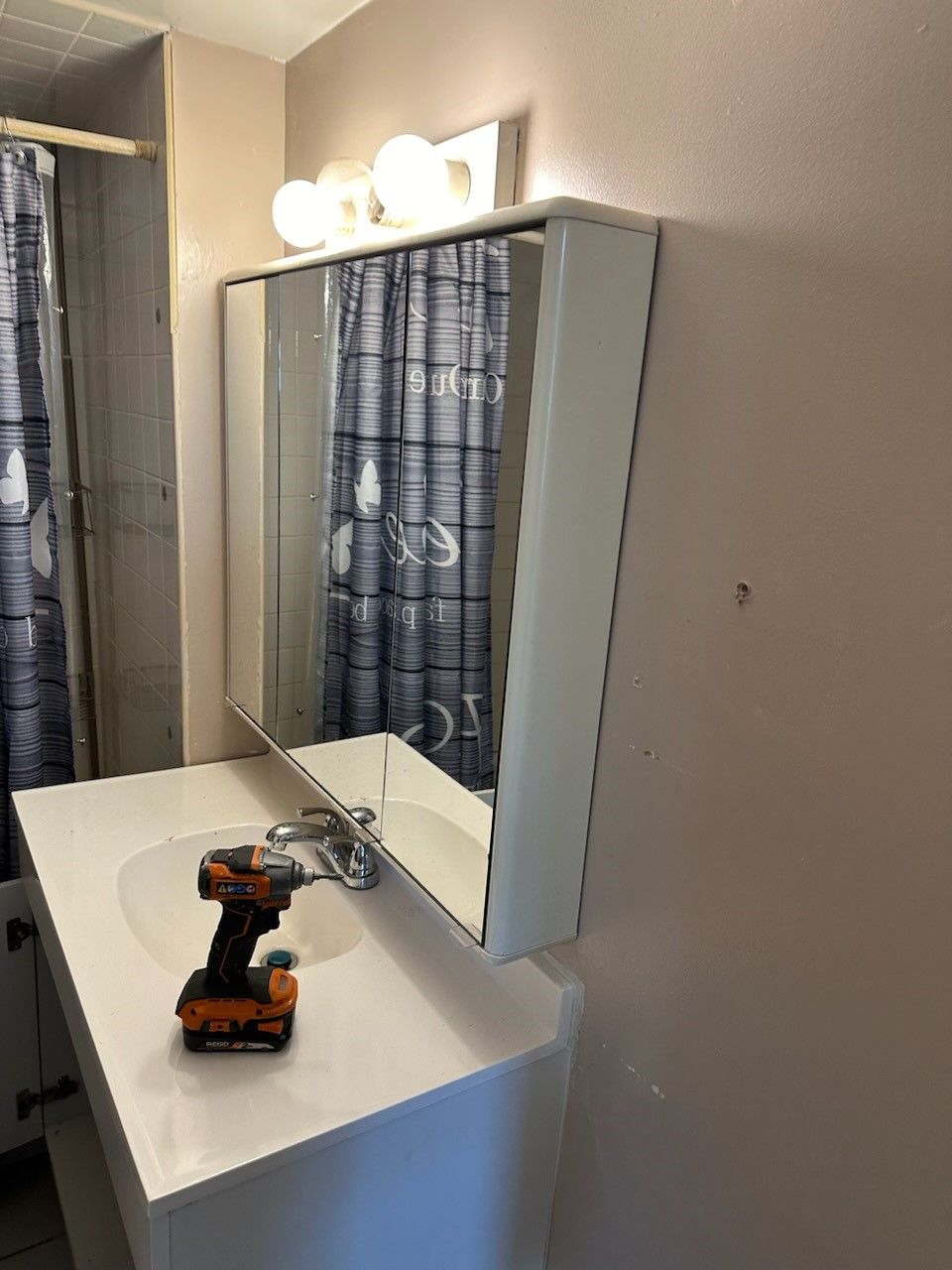A bathroom with a sink a mirror and a drill