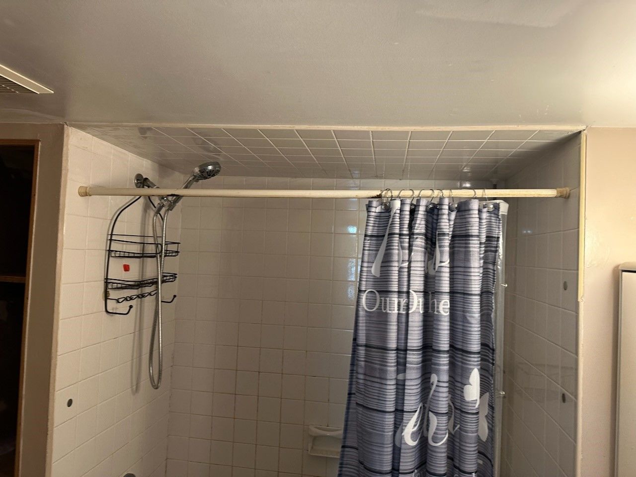 A bathroom with a shower curtain and a shower head.