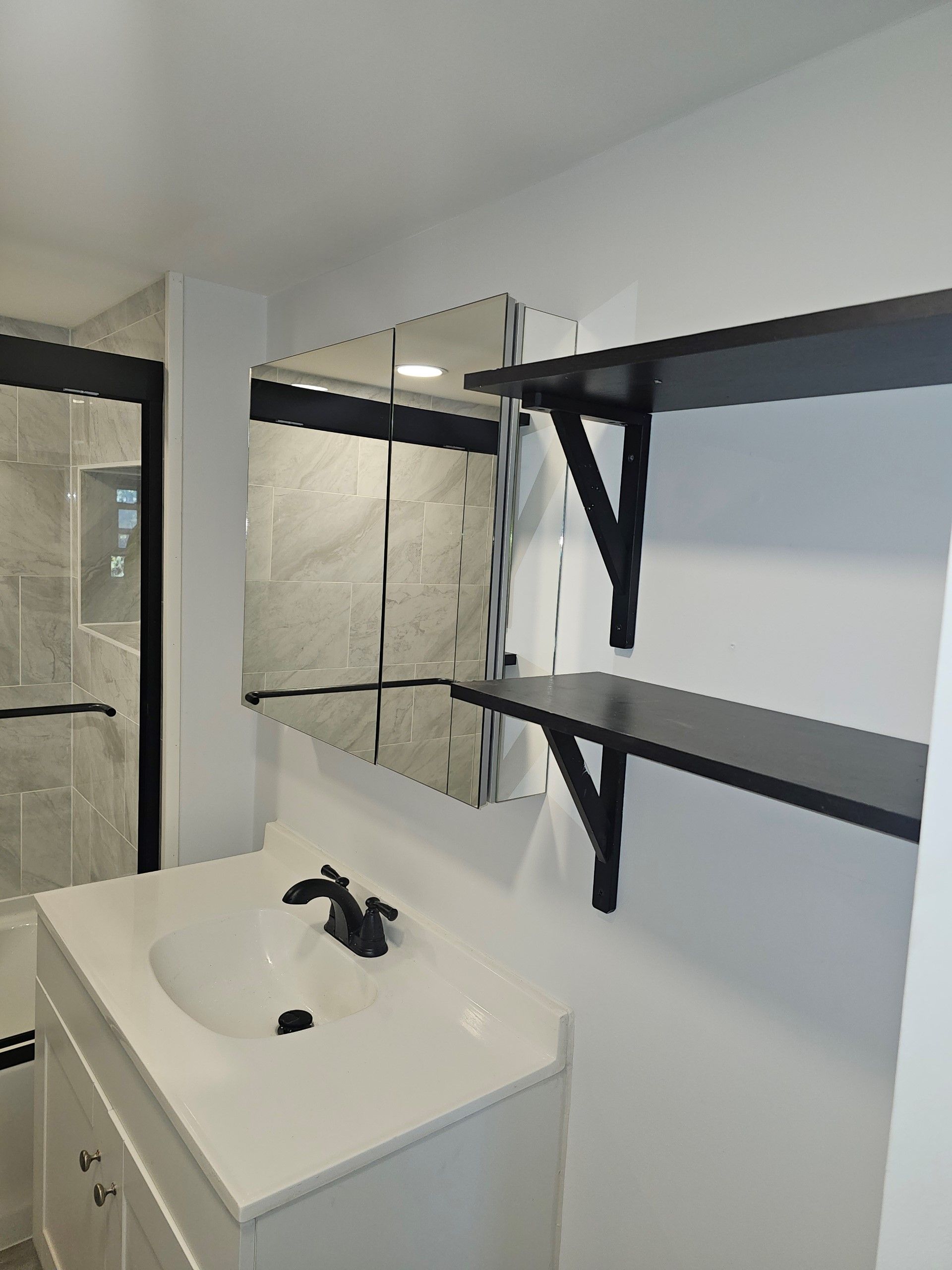 A bathroom with a sink, mirror and shelves