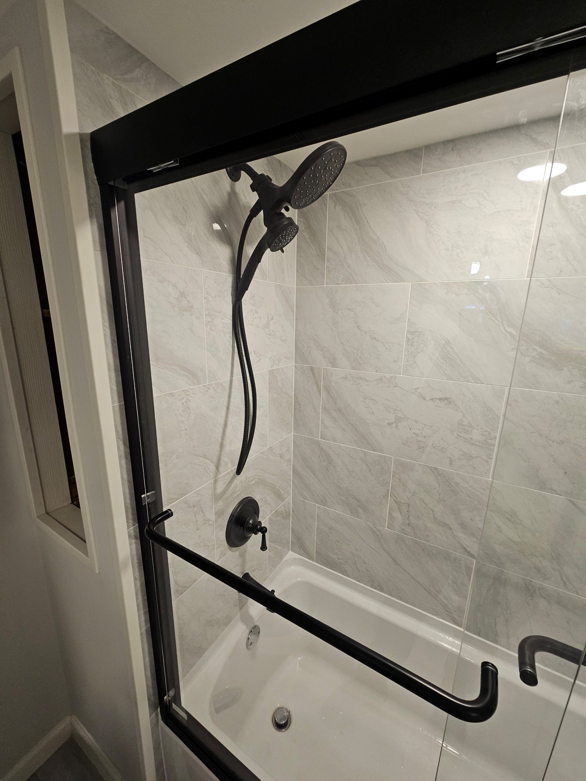 A bathroom with a bathtub and a shower with a sliding glass door.