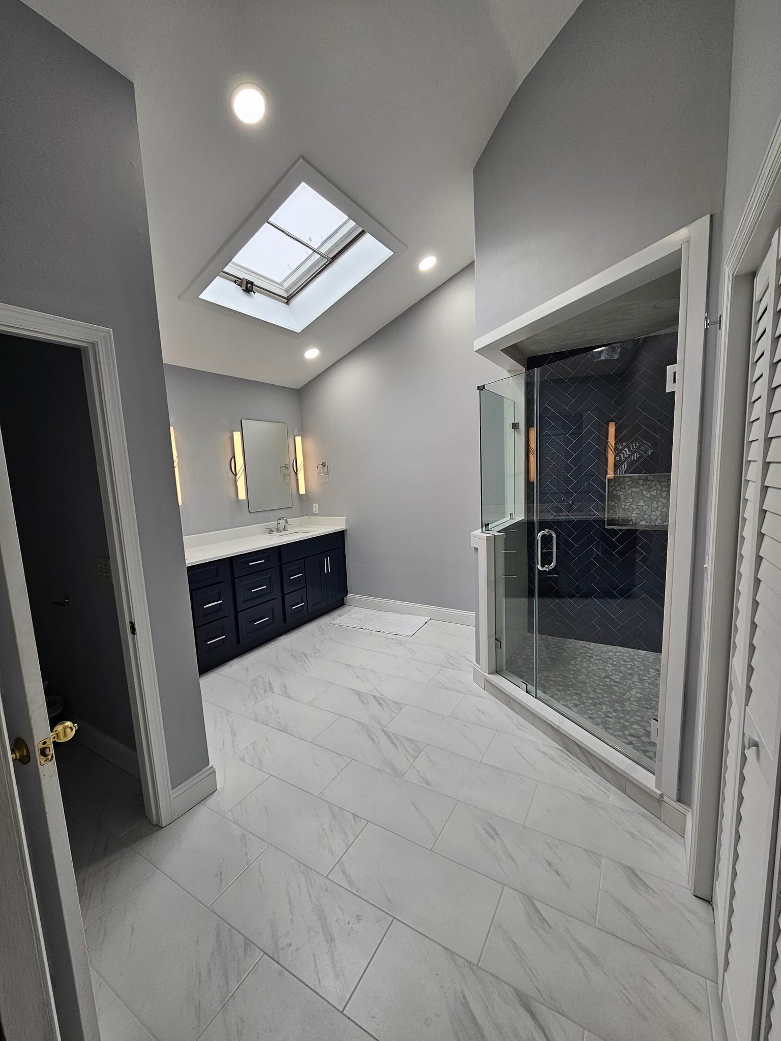A bathroom with a skylight and a walk in shower.
