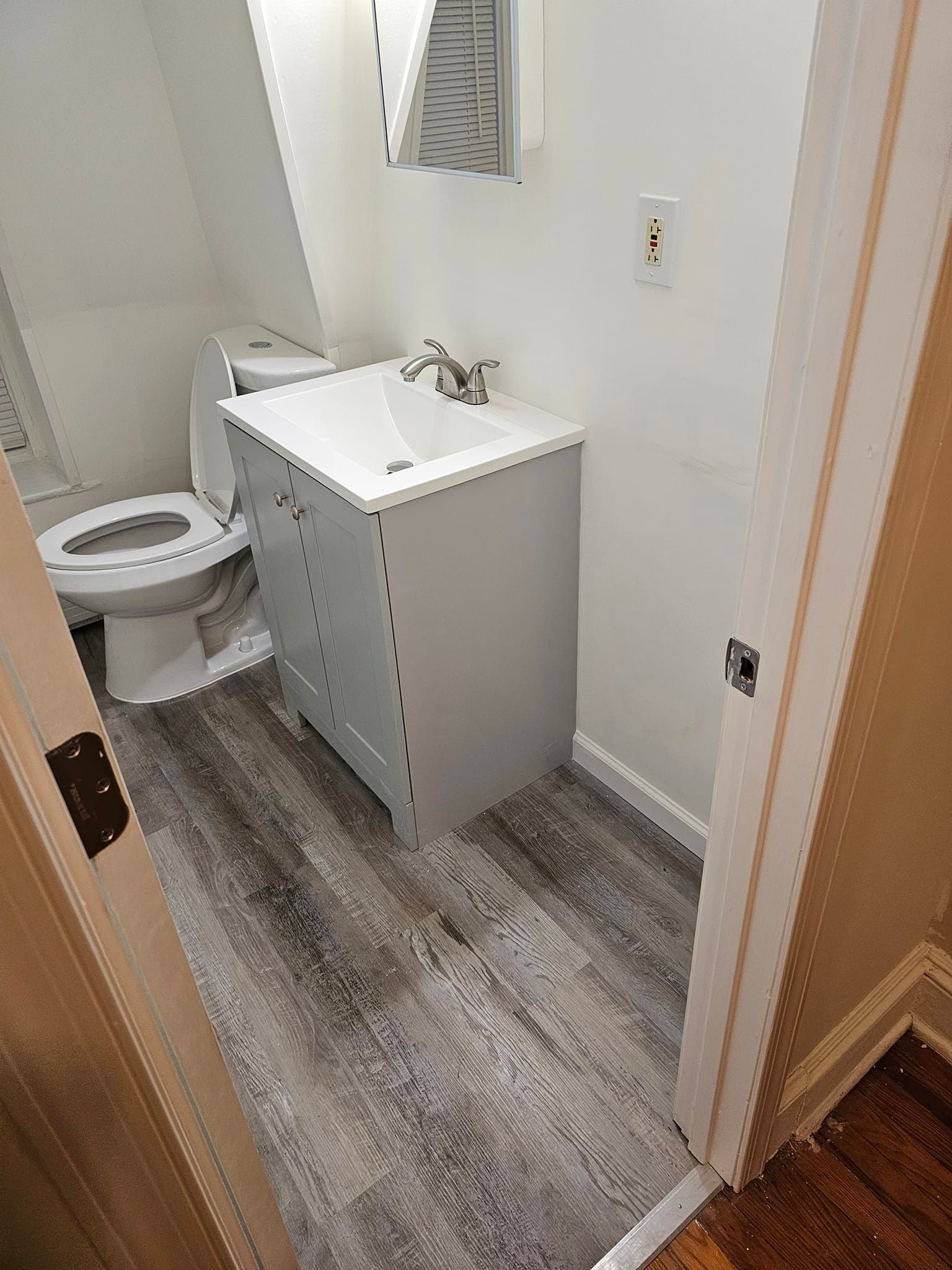 A bathroom with a sink, toilet and mirror.