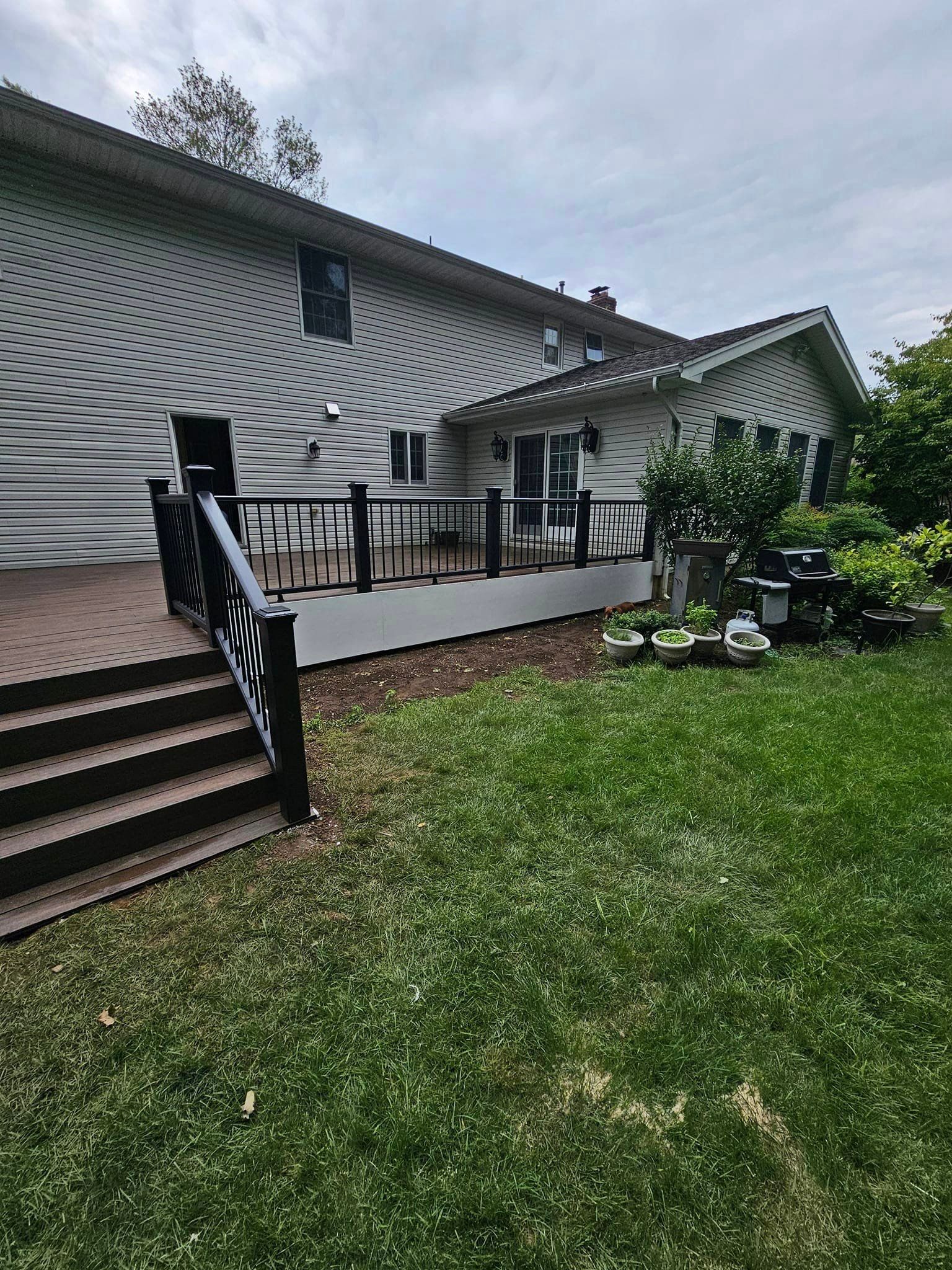 A large house with a large deck and stairs in the backyard.