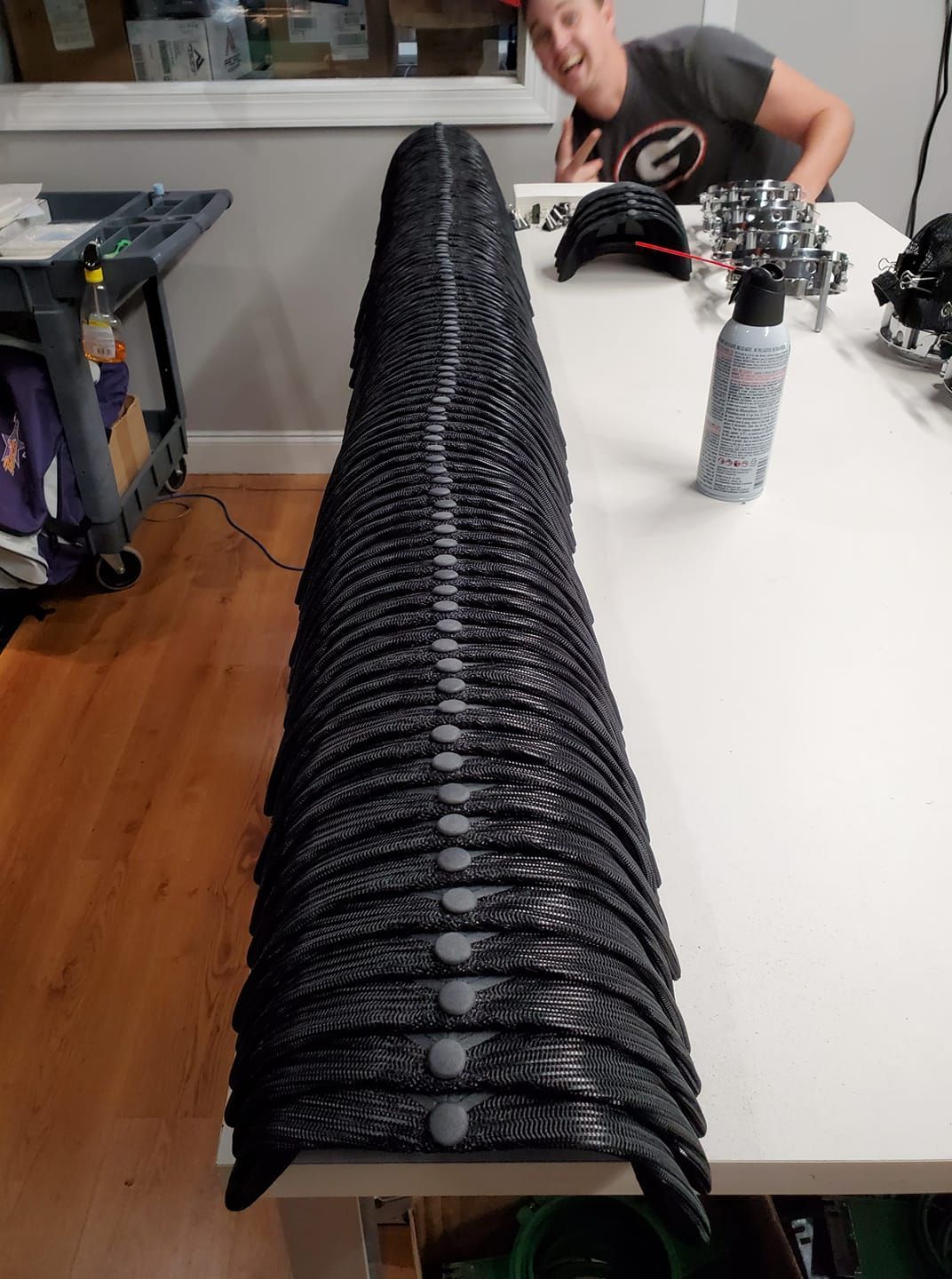 A woman is sitting at a table with a stack of black hats on it.