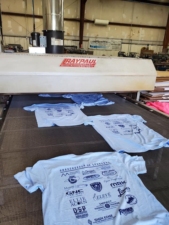 A machine is printing t-shirts on a conveyor belt in a factory.