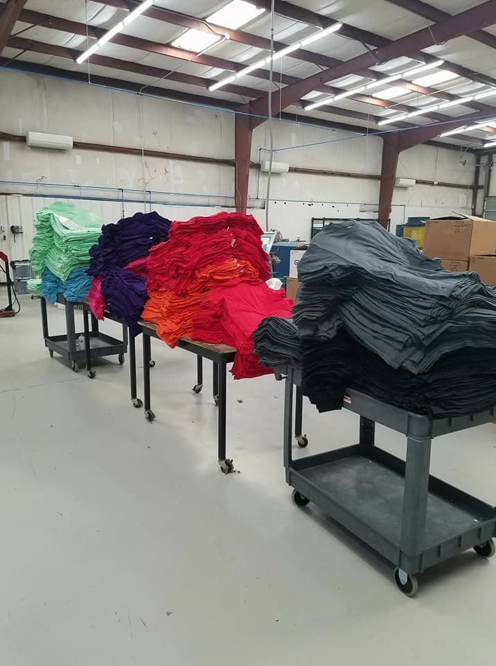 A warehouse filled with lots of colorful clothes on carts.