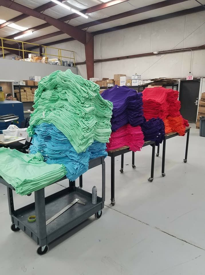 A bunch of towels are stacked on top of each other on a table in a warehouse.