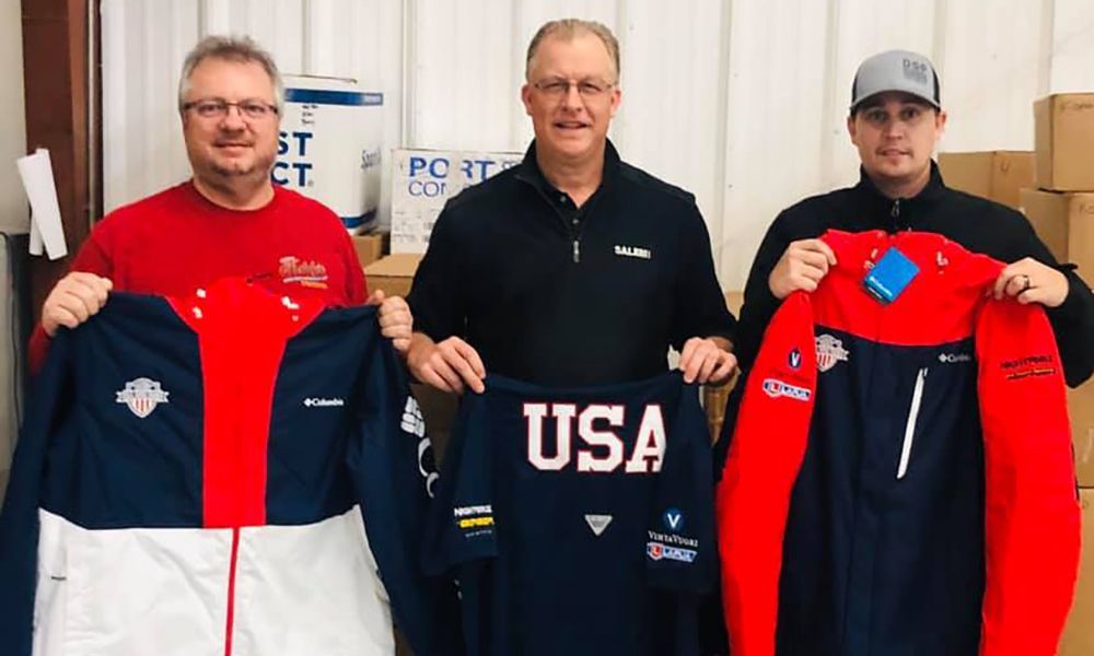Three men are holding up jackets with the word usa on them.