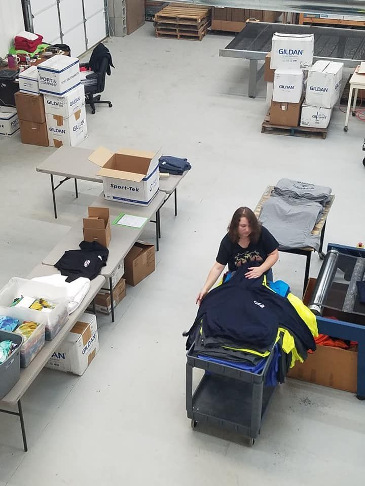 A woman is working in a warehouse with boxes and tables