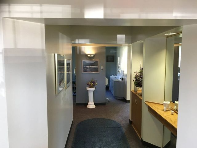 Hallway with doorways, artwork, and decorative furniture. Dark blue rug on the floor.