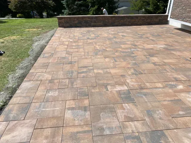 A brick walkway leading to a house next to a grassy field.