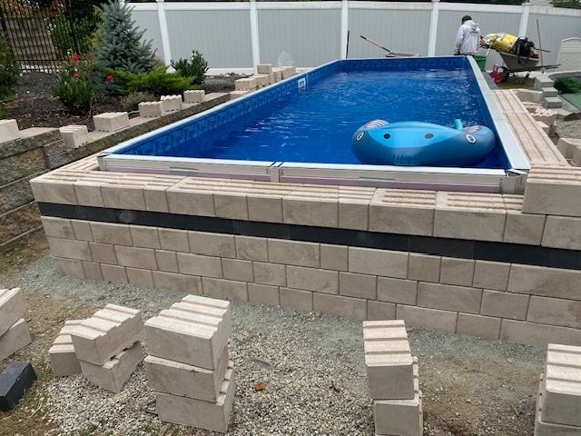 A swimming pool is being built with bricks and a blue raft in it.