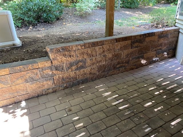 A brick wall is sitting on top of a brick patio.