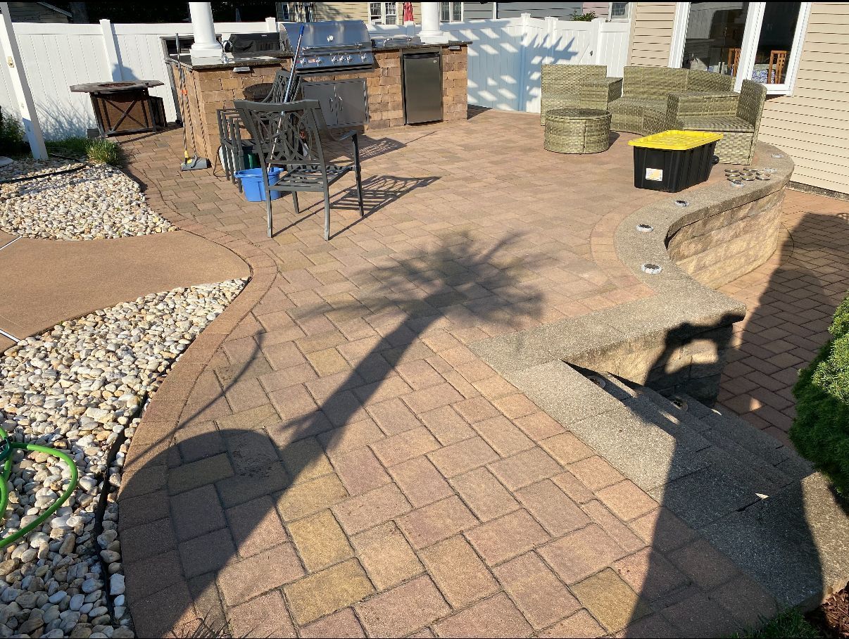 Brick patio with outdoor kitchen, shadow of a palm tree, and a dog.