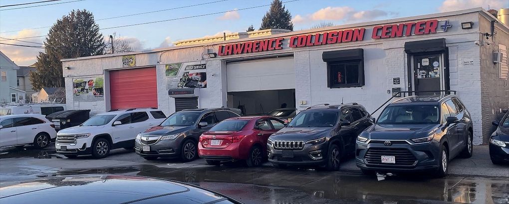 Exterior of the Performance Collision Center, a white building with several cars parked in the front lot.