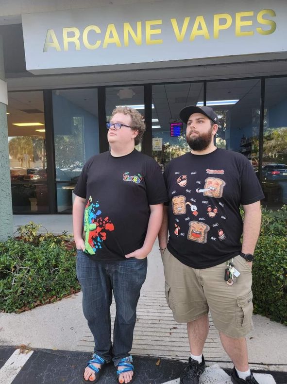 Two men standing in front of a store called Arcane Vapes