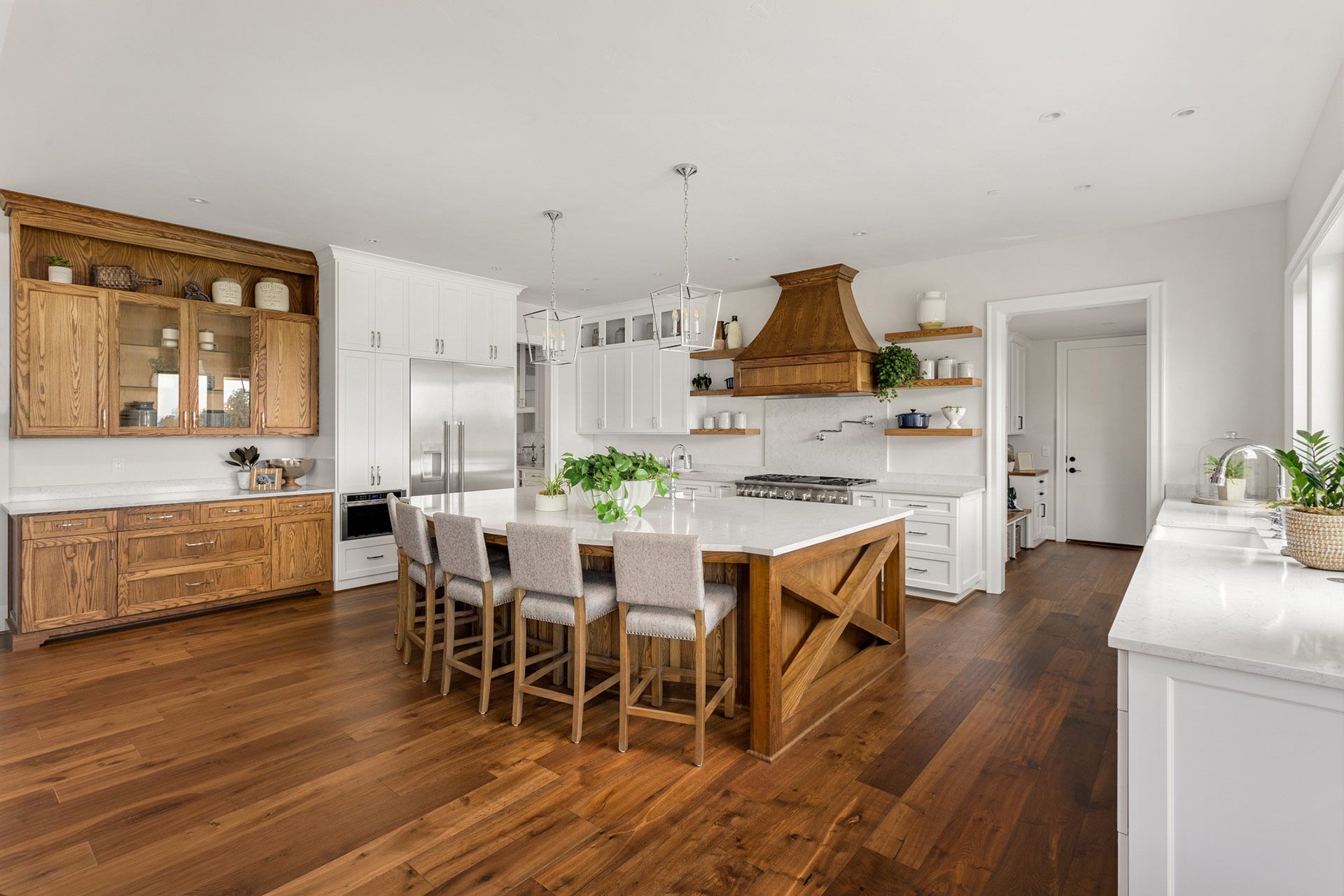 A kitchen with hardwood floors , white cabinets , and a large island.