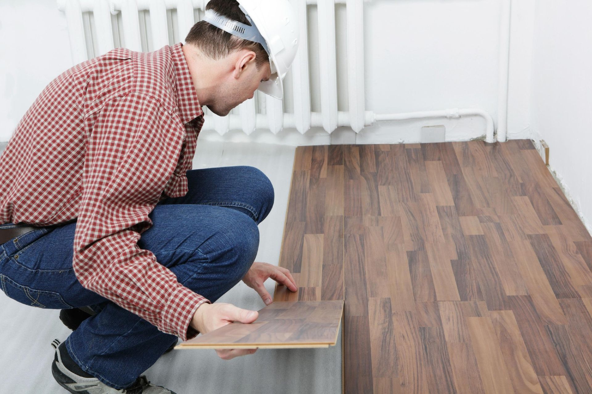 A man is installing a wooden floor in a room.