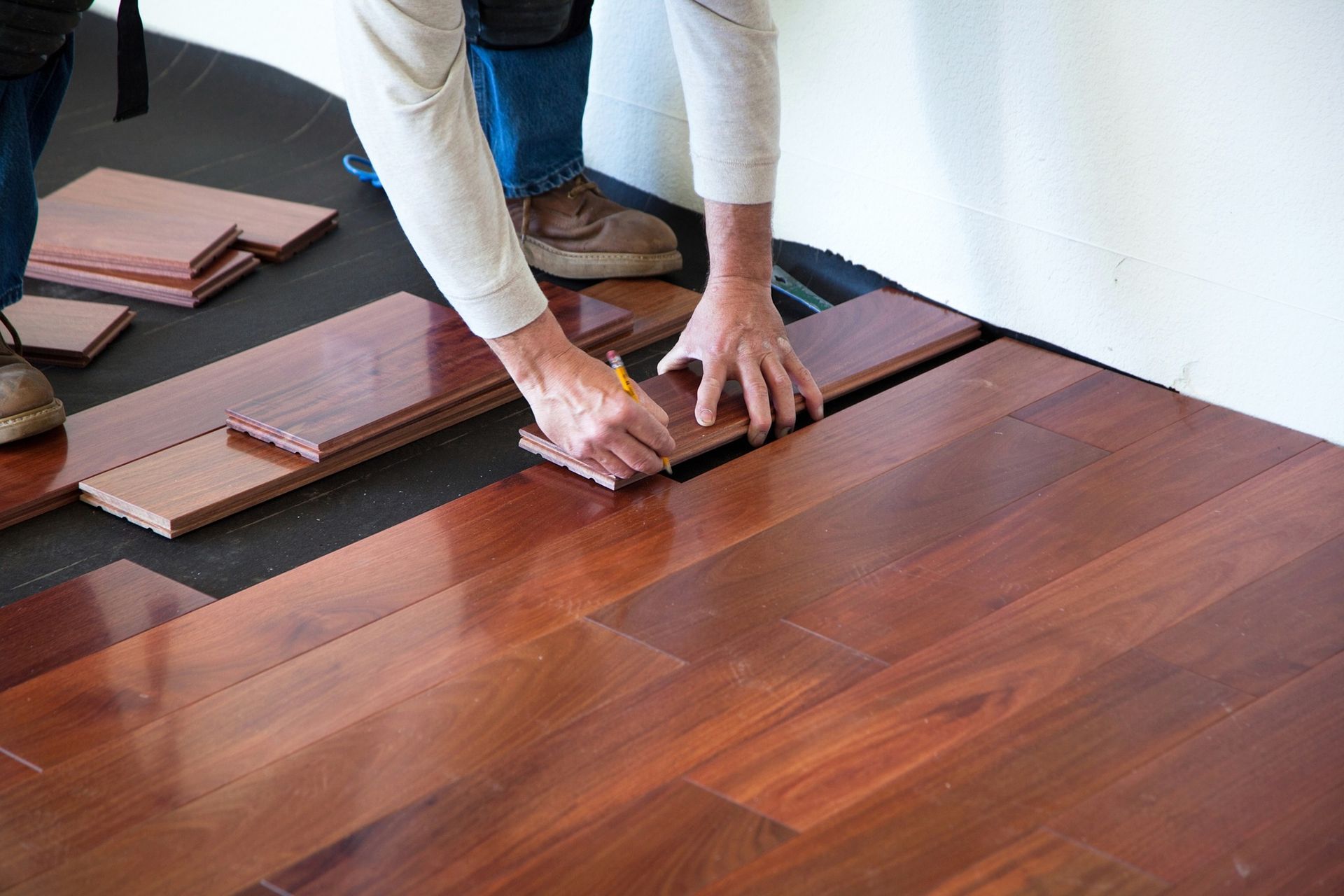 A man is installing a hardwood floor in a room.
