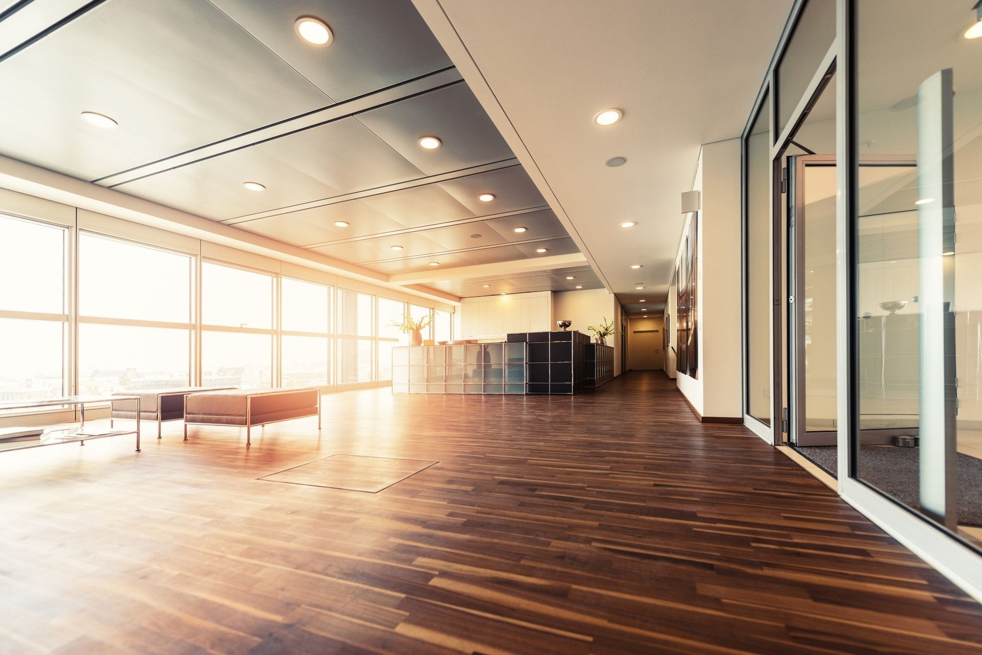 A long hallway in an office building with a wooden floor and lots of windows.