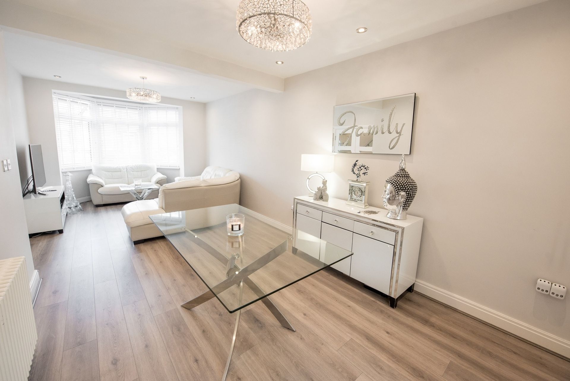 A living room with a glass table and a sign on the wall that says `` family ''.