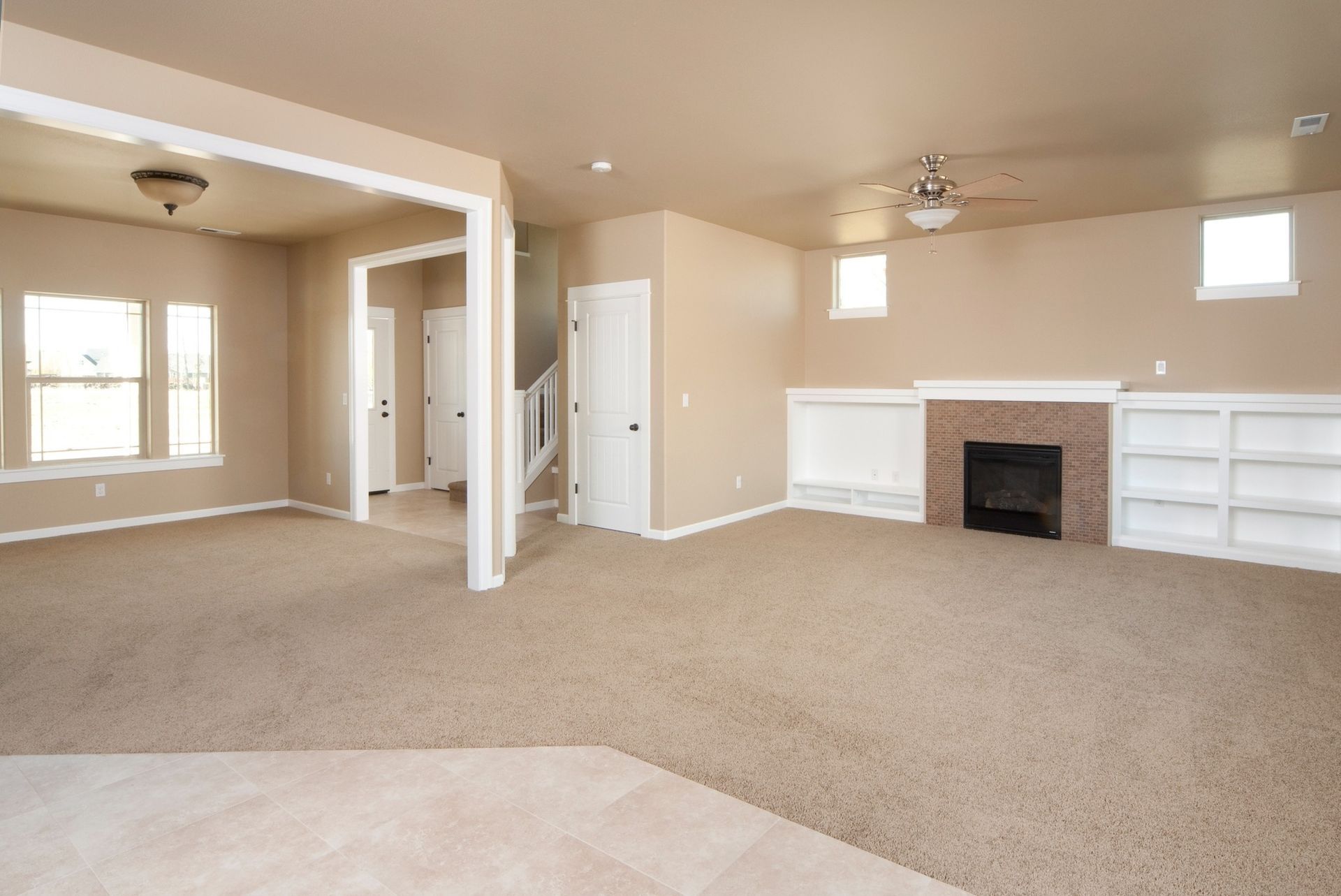 An empty living room with a fireplace and a ceiling fan.