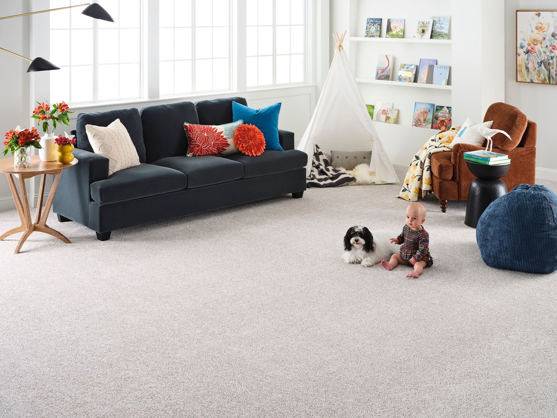 A living room with a couch , chairs , a baby and a dog.
