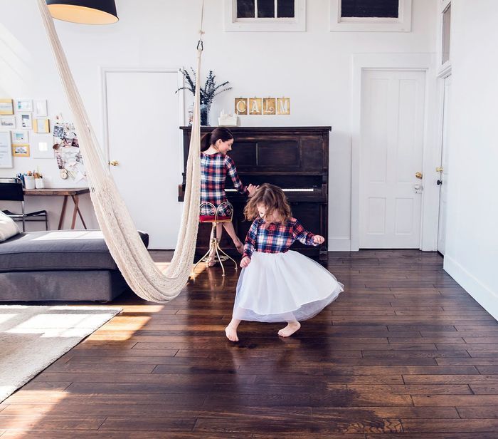 A woman and a little girl are dancing in a living room