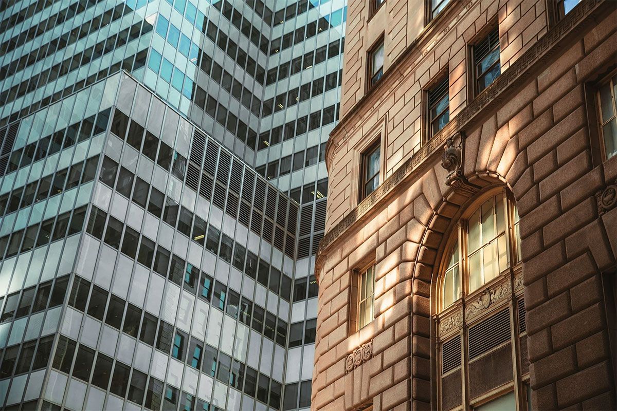 Downtown skyscrapers beside an older brick building with arched windows