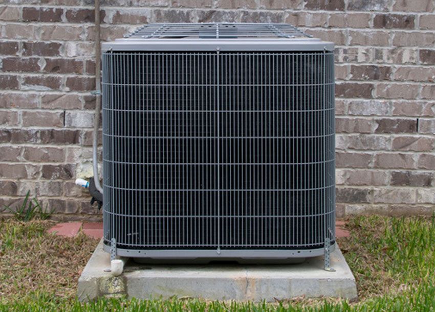 Outdoor air conditioning unit against a brick wall.